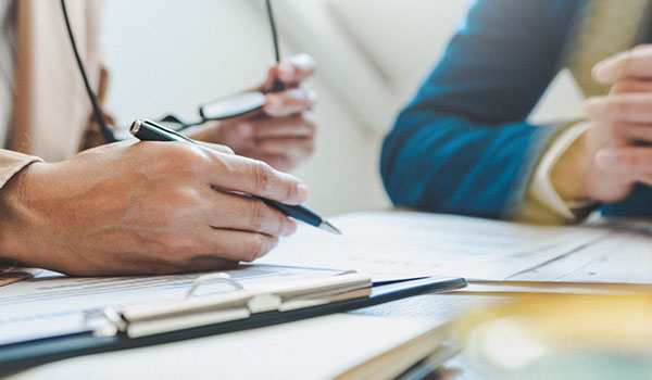 two hands holding pens writing on documents in a meeting discussing seven important points
