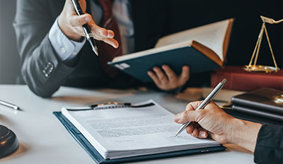 two people engaged in a legal discussion reviewing documents while a book and legal scale are visible focused on the importance of contract law and the seven key principles
